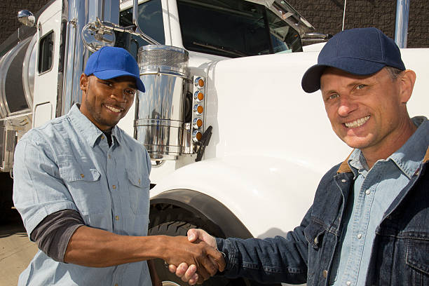 A royalty free image from the trucking industry of two truck drivers shaking hands in front of a semi truck.